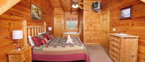 A cozy wooden cabin bedroom with a bed, dresser, and a ceiling fan.