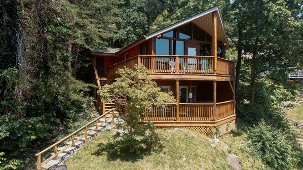 Eine zweistöckige Holzblockhütte mit Balkon, umgeben von dichtem Wald.