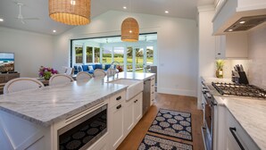 A modern kitchen with a large island, white cabinetry, and a gas stove.