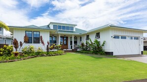 A two-story house with a green roof, a front porch, and a garage.