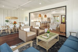A spacious living area with a dining set, wicker furniture, and a view into the kitchen.