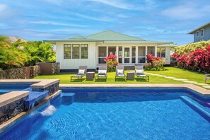 A residential property with a swimming pool, a covered patio with lounge chairs, and a well-maintained garden.