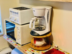 A coffee maker with a glass carafe and a toaster on a kitchen counter.