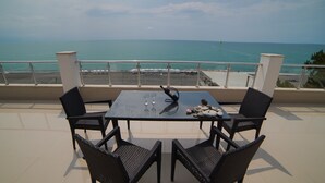 Un balcone con tavolo e sedie affacciato su una spiaggia.