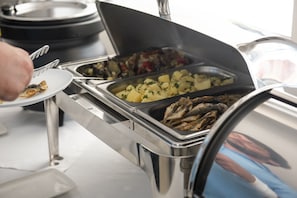 Una mesa de buffet con diversos alimentos, incluyendo patatas y pescado.