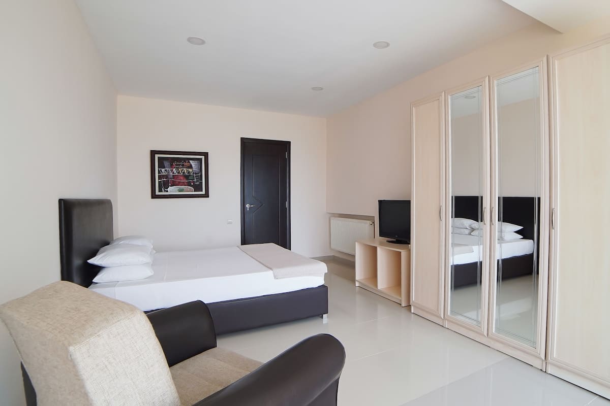 A modern bedroom with a bed, a TV, a wardrobe, and a chair.