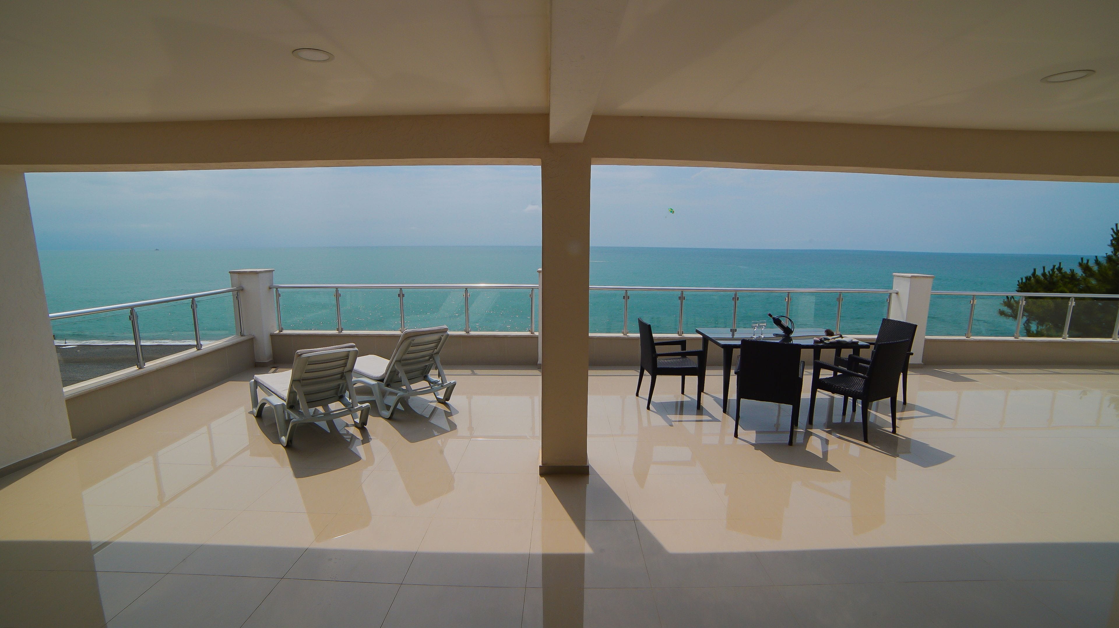 Un balcón con vista al mar, amueblado con sillas y una mesa.