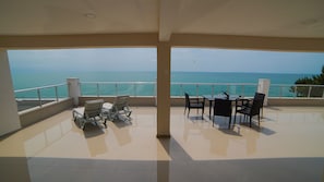 Un balcón con vista al mar, amueblado con sillas y una mesa.