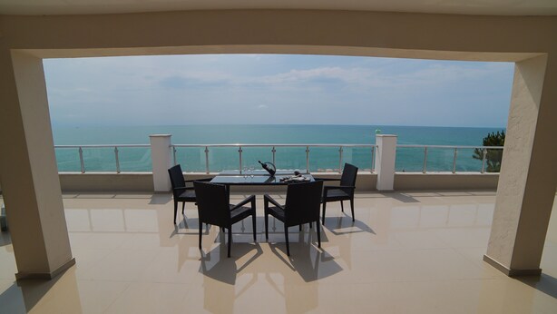 Un balcone con tavolo e sedie, vista su un mare cristallino e blu.