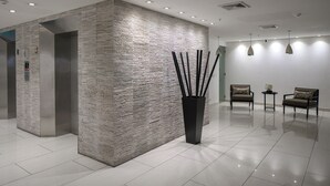 A modern lobby with a textured wall, a reception desk, two chairs, and pendant lighting. - PANAMA CANAL & PANAMA CITY - FULL OCEANFRONT APARTMENT (Panamá City)