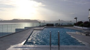 A swimming pool with a glass railing, surrounded by a paved deck and potted plants. - PANAMA CANAL & PANAMA CITY - FULL OCEANFRONT APARTMENT (Panamá City)