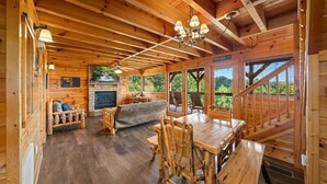 L’intérieur d’une cabane en rondins, avec une cheminée, des meubles en bois et un coin repas.