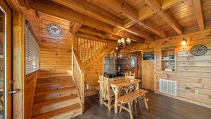 L’intérieur d’une cabane en bois comprend un escalier, une table à manger avec des chaises et un coin cuisine.