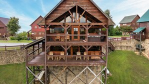 Une cabane en rondins à deux étages, dotée d’un balcon et d’un espace extérieur aménagé pour s’asseoir.