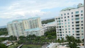 A high-rise hotel with multiple floors, a swimming pool, and a water canal. - One bedroom apt just 1 mile to the beach with pool, gym, and playroom! (Boynton Beach)