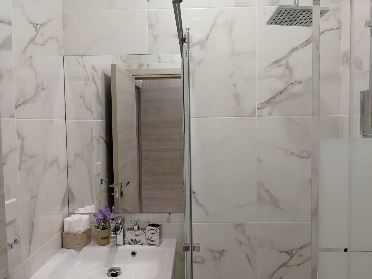 A bathroom with a shower, a sink, and a mirror.