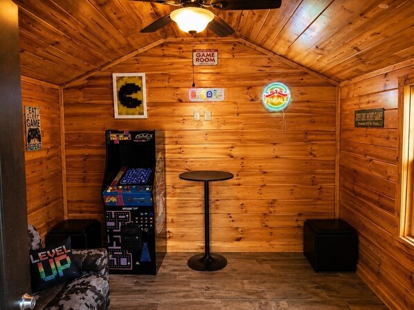 A cozy room with wooden walls, a ceiling fan, a neon sign, and a Pac-Man arcade game. - Key Bluff: Unlock Your Mountain Escape (Sevierville)