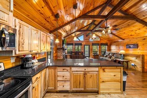 A spacious kitchen with wooden cabinets, a granite countertop, and a central island. - Key Bluff: Unlock Your Mountain Escape (Sevierville)