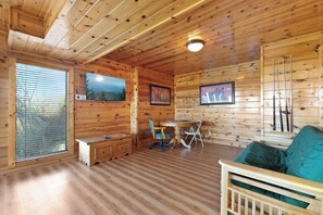 Interno di una baita di legno con un tavolo da pranzo, sedie, una panca e un divano.