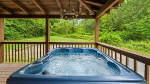 A hot tub under a wooden pergola with a view of a forested area. - Adjust Your Altitude: Elevate Your Escape (Sevierville)