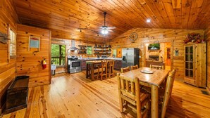 A log cabin interior with a kitchen, dining area, and a fireplace. - Adjust Your Altitude: Elevate Your Escape (Sevierville)