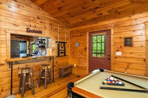 Enjoy a game of pool and a cocktail at this stylish room's bar area, featuring a billiards table and comfortable seating.