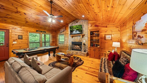 A cozy cabin interior with a pool table, comfortable seating, a fireplace, and a television. - Adjust Your Altitude: Elevate Your Escape (Sevierville)