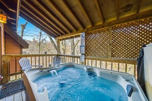 Ein Whirlpool auf einer Holzterrasse mit Stühlen, umgeben von einem Holzzaun mit Beleuchtung.
