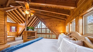 Camera accogliente in legno con un letto, una TV su uno scaffale in legno e una finestra che si affaccia su una foresta.