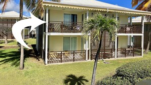 A two-story hotel with balconies, a covered outdoor area, and a well-maintained lawn.