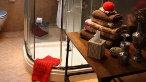 A modern bathroom with a glass-enclosed shower, a wooden vanity with toiletries, and a visible toilet.