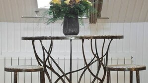 A metal table with a unique twisted design, a vase with flowers, and a window in the background.