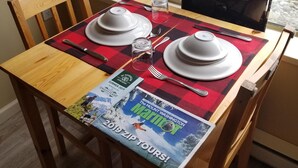 Une table à manger dressée avec des assiettes, des couverts et un magazine.