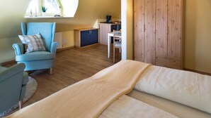 Une pièce chaleureuse comprenant un canapé, un fauteuil, une armoire en bois, un petit coin cuisine et une fenêtre offrant une vue panoramique.