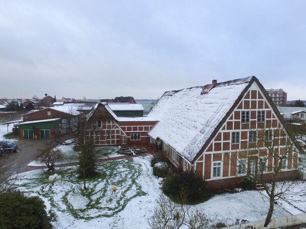 A residential area with traditional red brick houses, a green building, and a snow-covered landscape.