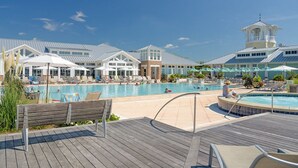 A resort pool area with lounge chairs, umbrellas, and a wooden deck.