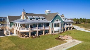 A large, two-story building with a wrap-around porch, multiple windows, and a tower-like structure on the roof.