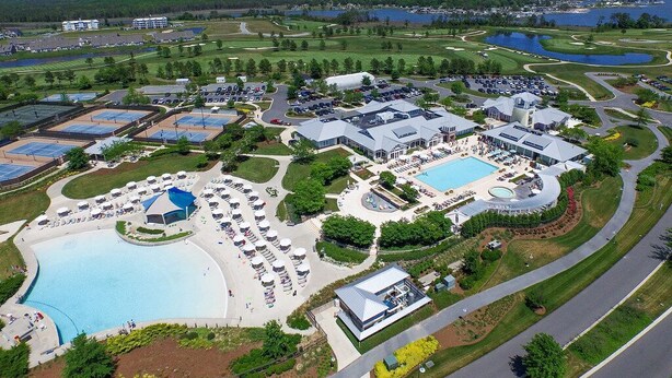 An aerial view of a resort with multiple swimming pools, a golf course, and a large parking area.