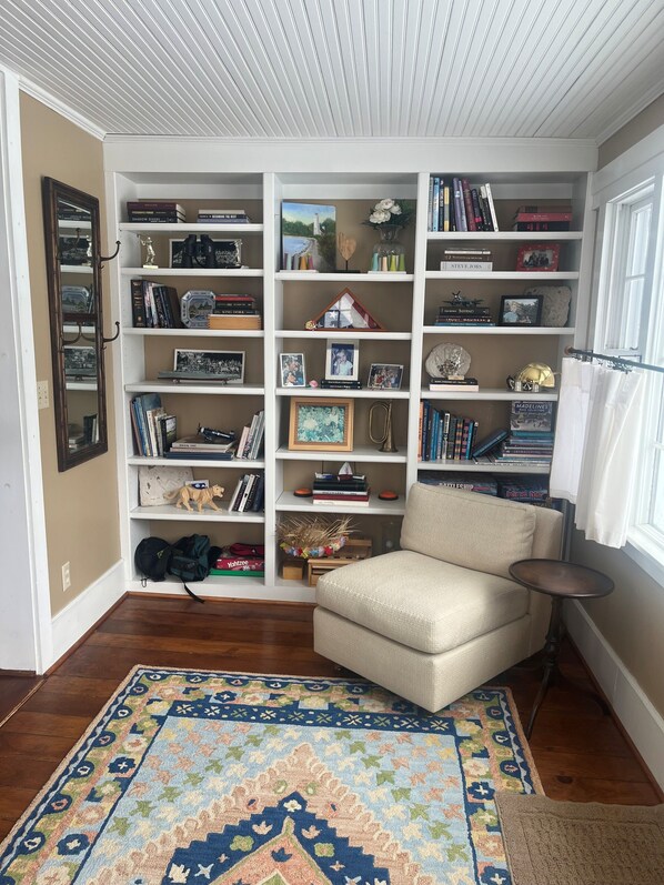 Una sala acogedora con una estantería, un sillón color beige y una alfombra estampada.