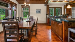 A spacious kitchen with wooden cabinetry, a large island, and a dining area with a wooden table and chairs.