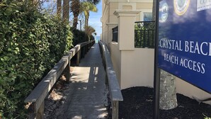 A pathway leading to Crystal Beach Beach Access with a signboard, surrounded by lush greenery and palm trees. - STEPS TO CRYSTAL BEACH see picture for location (Destin)