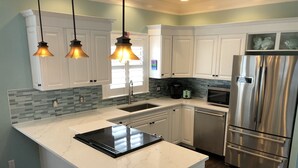 A modern kitchen with white cabinetry, a stainless steel refrigerator, and a marble countertop. - STEPS TO CRYSTAL BEACH see picture for location (Destin)