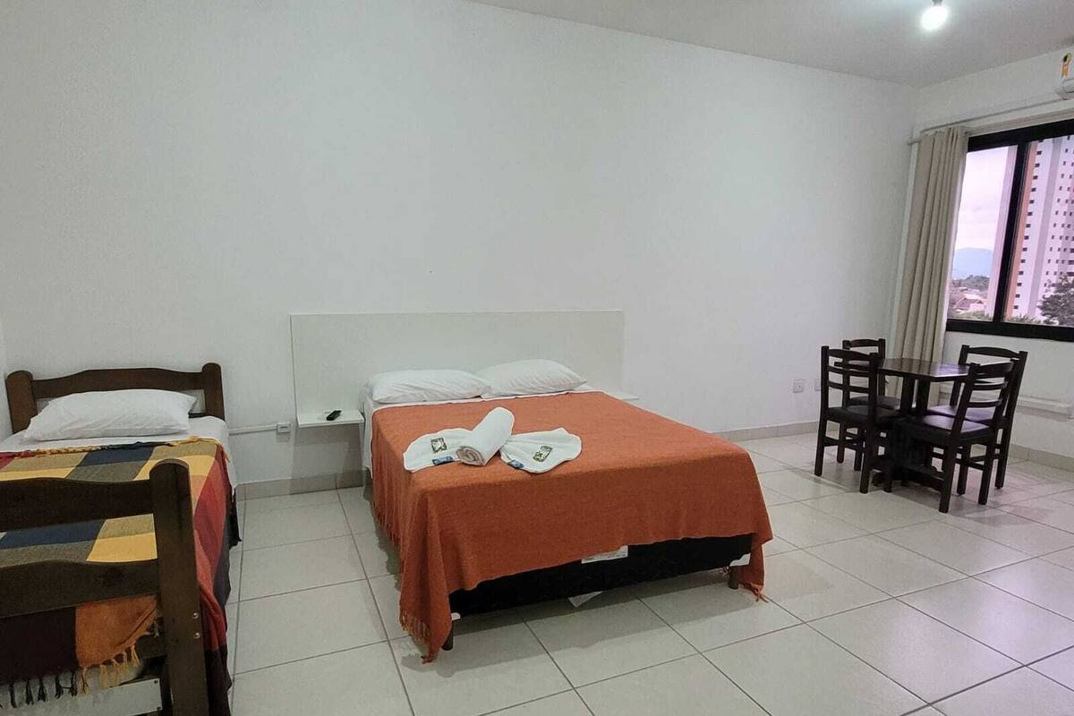 Une chambre d’hôtel avec un lit, une petite table avec des chaises et une fenêtre donnant sur des immeubles.