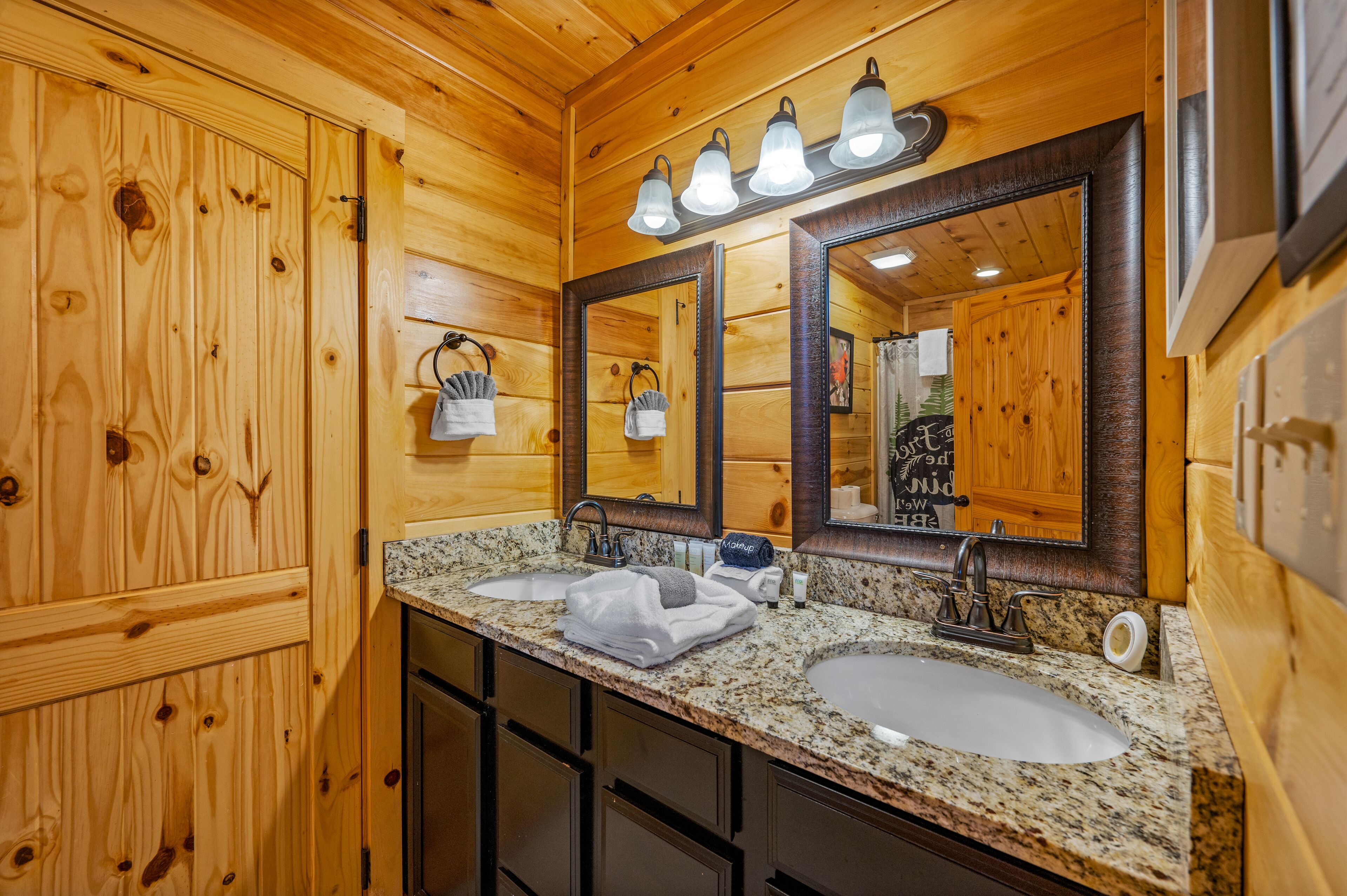 Un baño tipo cabaña de madera con dos lavamanos, un espejo grande y un mueble de tocador.