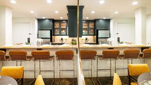 Una cucina moderna con mobili scuri, un'isola centrale e sgabelli da bar.