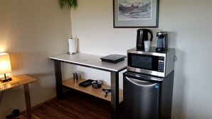 A compact kitchenette with a microwave, coffee maker, and a small refrigerator. - Fort Wrangell, Orca Room (Wrangell)