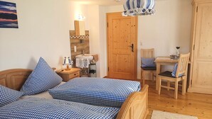 Un dormitorio con cama de madera, escritorio, silla, armario de madera y baño con espejo y lavamanos.
