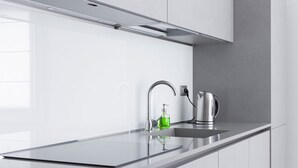 Una cocina moderna con un lavamanos de acero inoxidable, una tetera y un dispensador de jabón.