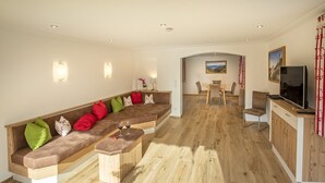 Una sala de estar moderna con sofá integrado, piso de madera y una zona de comedor con mesa y sillas.