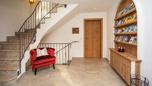 A staircase with a red sofa, a wooden door, and a bookshelf filled with books. - (4) Ferienwohnung für 1-4 Personen (63 qm, OG) (Bernau am Chiemsee)